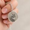 Silver Memorial Pendant — held between two fingers for scale Silver Memorial Pendant — held between two fingers for scale